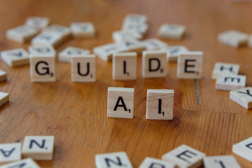 A wooden table topped with scrabble tiles that spell out the word guide all